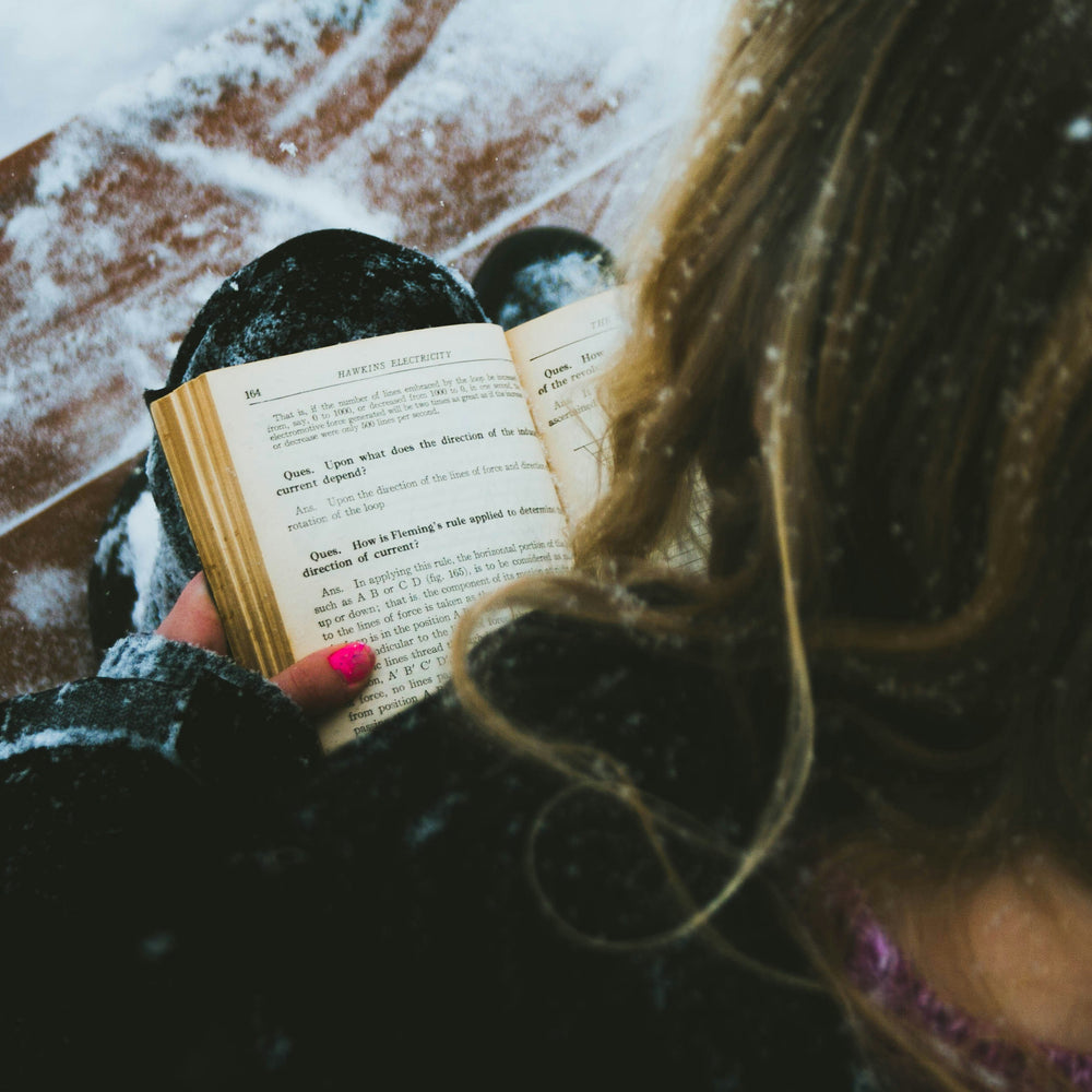 Photo by Will on Unsplash  of a girl reading in the snow